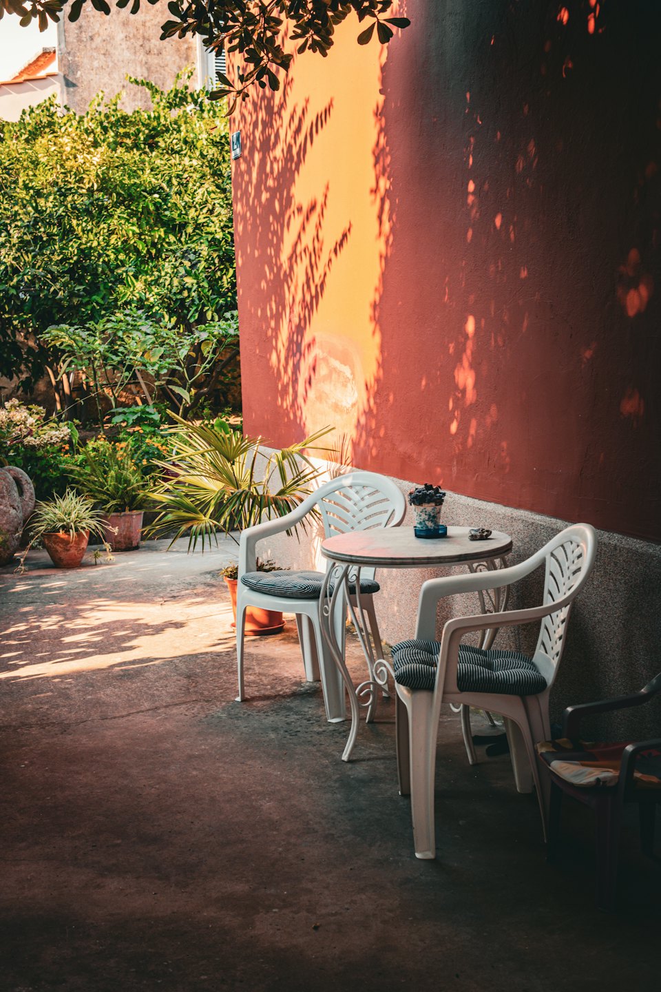 Un tavolo e sedie in metallo bianco sono disposti su un patio.