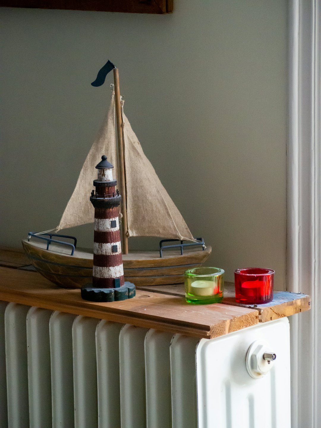 Oggetti decorativi nautici su una mensola di legno accanto a una finestra.