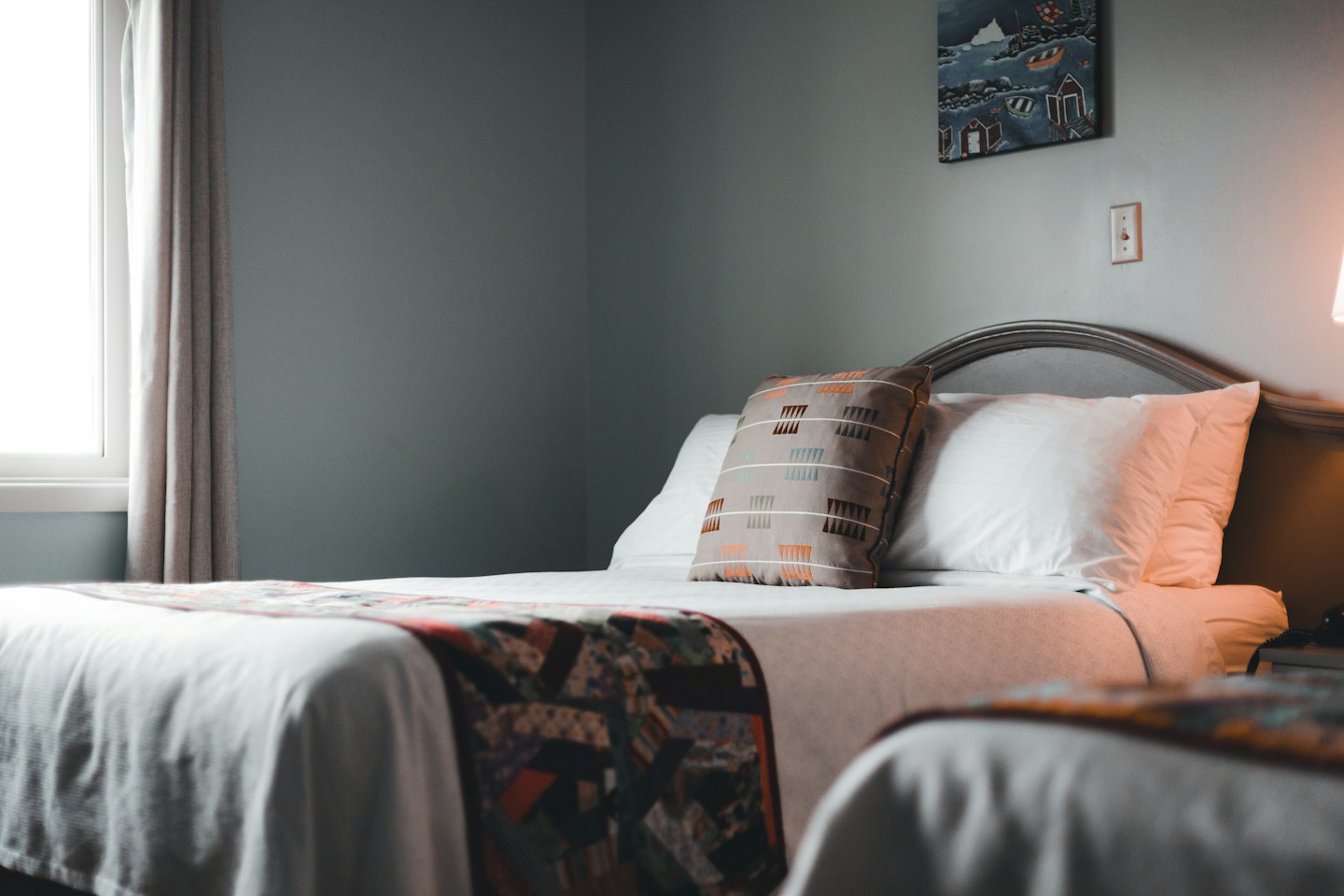 Due letti d'albergo con lenzuola bianche e cuscini decorativi.