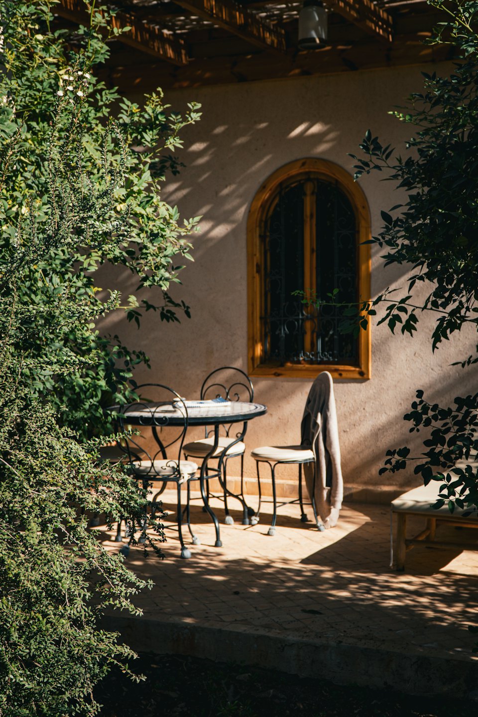 Tavolo e sedie in ferro battuto su un patio esterno illuminato dal sole.