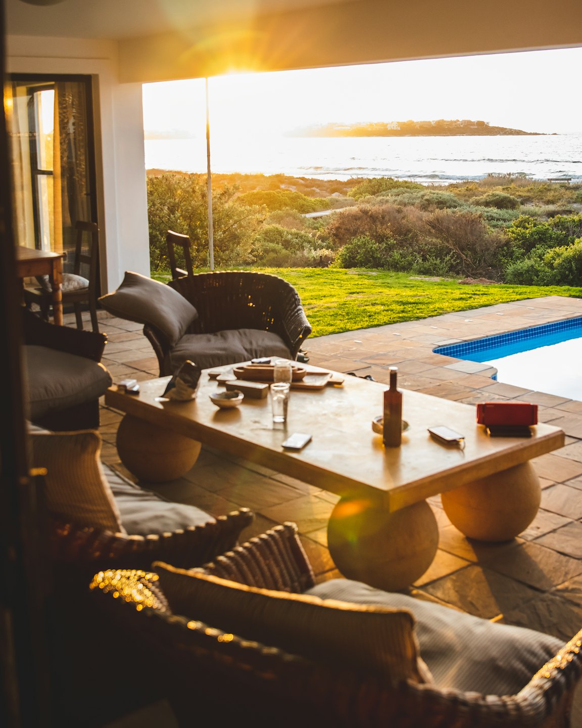 Mobili in vimini su un patio con vista su una piscina e sull'oceano.